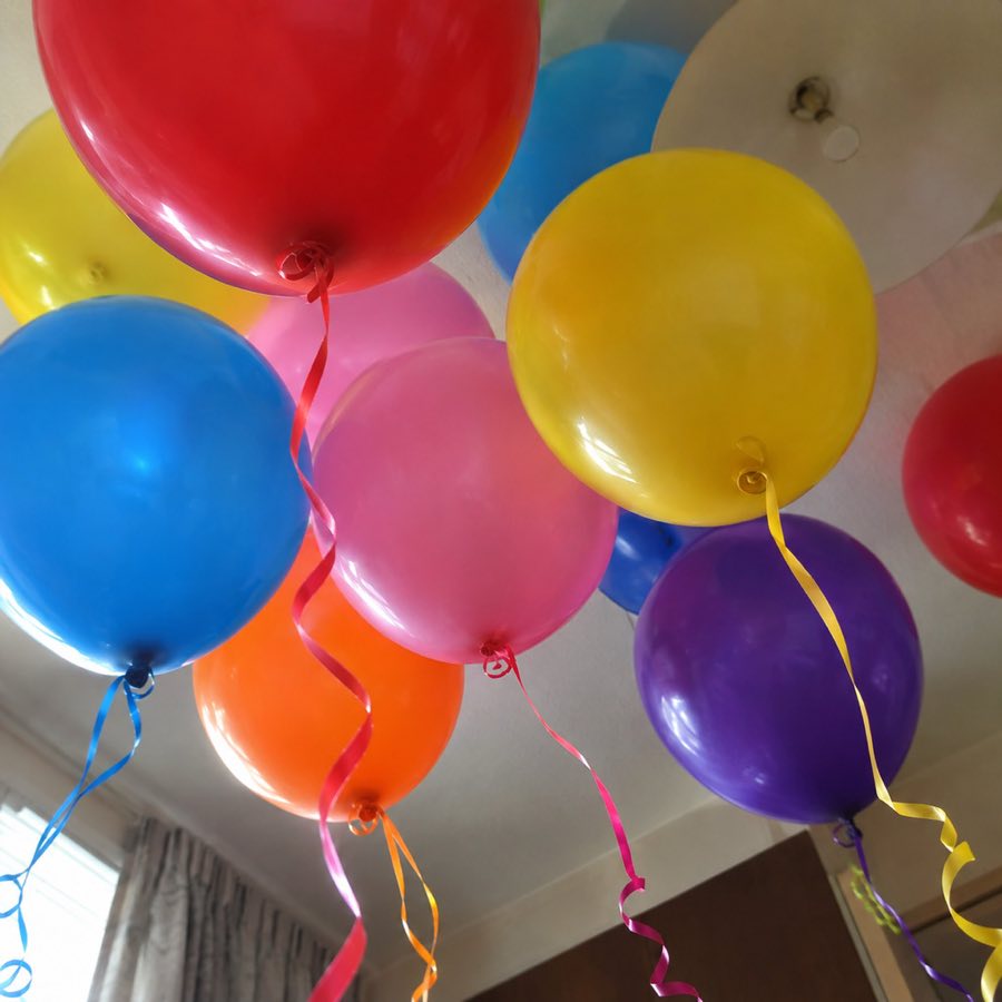 Birthday balloons against a ceiling, photographed from underneath