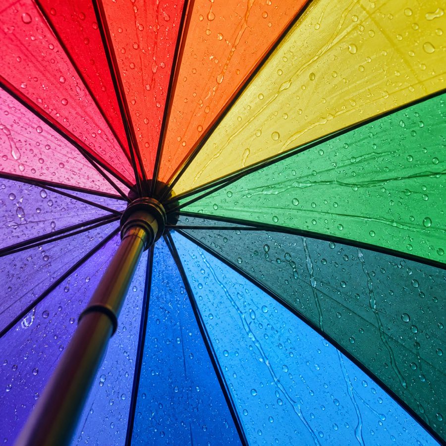 A rainbow umbrella from directly underneath, rain on it